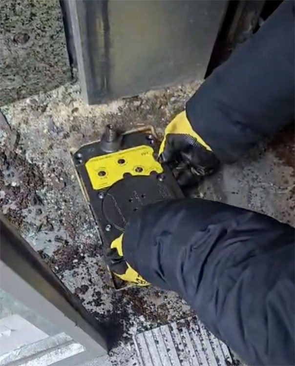 Technician installing a Rixson floor-mounted door closer for a commercial glass door in NYC